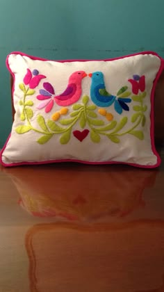 a decorative pillow with two birds on it