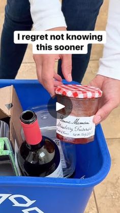 a person is picking up some wine from a trash can