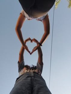 two people making a heart shape with their hands while standing on top of each other