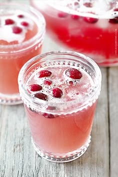 two glasses filled with drinks sitting on top of a wooden table