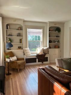 a living room filled with lots of furniture and bookshelves next to a window