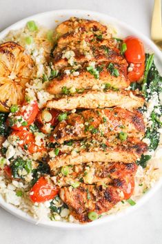 a white plate topped with chicken, rice and veggies next to a fork