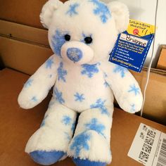 a blue and white teddy bear sitting on top of a cardboard box