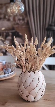 a vase with some plants in it sitting on a table next to plates and cups