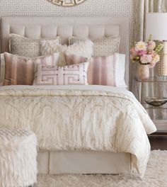 a bedroom with a large bed covered in lots of pillows and blankets, along with a mirror on the wall