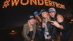 four women pose for a photo in front of the wonder ride sign at night time