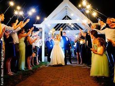 a bride and groom walking down the aisle with sparklers in their hands at night