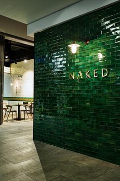 a green tiled wall with the word naked written on it in gold letters and lights