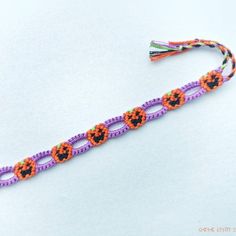 an orange and purple beaded halloween bracelet with pumpkins on the end, sitting on a white surface