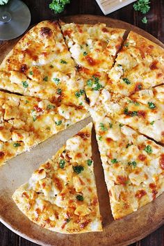 a pizza on a wooden platter with slices cut out and ready to be eaten