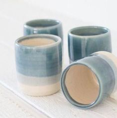 three ceramic cups sitting on top of a white wooden table with one cup in the middle