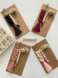 four different tassels are displayed on brown cards with white beads and pink tassels