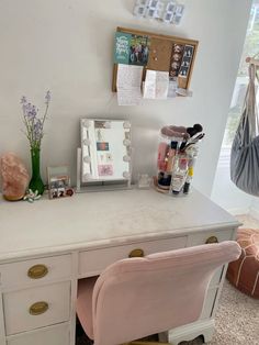 a white desk topped with a pink chair next to a mirror and other items on top of it