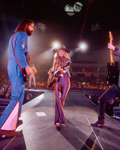 two people on stage with one playing guitar and the other holding an electric guitar in his hand