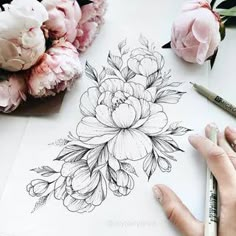 a person is drawing flowers on paper with markers and pencils next to it are pink peonies