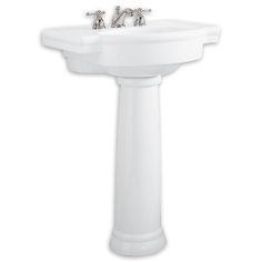 a white pedestal sink with two faucets on it