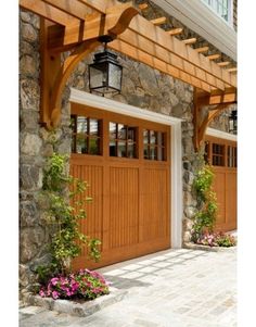 two wooden garage doors with flowers in the planters on either side and an attached light fixture above them