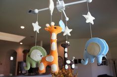 three stuffed animals hanging from the ceiling in a living room or dining room, one is giraffe and the other is an elephant