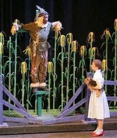 two children are standing on stage with an scarecrow