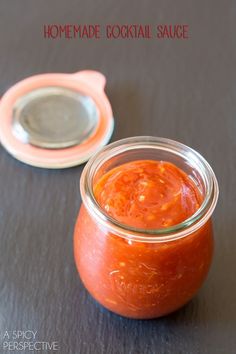 an orange sauce in a glass jar next to a spoon on a gray surface with text overlay that reads homemade cocktail sauce