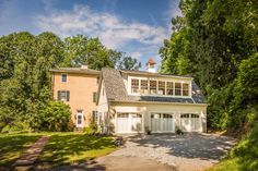 a two car garage sits in front of a large house with lots of trees around it