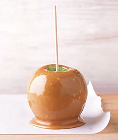 a caramel apple on a white plate with a toothpick sticking out of it