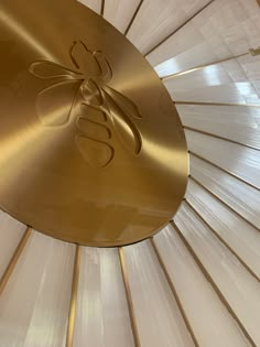 the inside of a gold colored umbrella with an insect on it's center piece