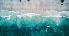 an aerial view of the ocean with waves and surfers