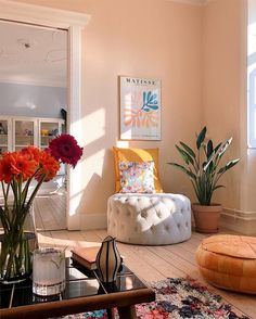 a living room filled with lots of furniture and flowers in vases on the floor