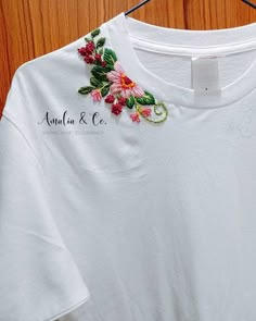 a white t - shirt with pink flowers on the front and green leaves on the back