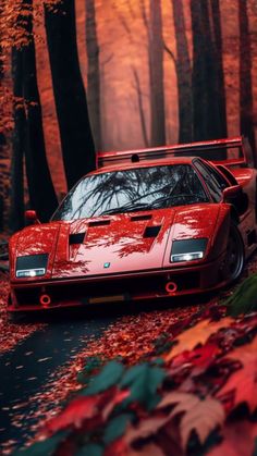 a red sports car parked on the side of a road surrounded by trees and leaves