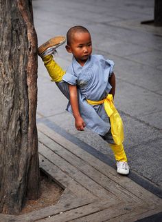 a little boy standing next to a tree