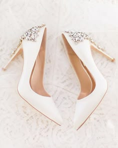 a pair of white wedding shoes with jeweled details on the toes and heels are laying on a lace covered surface