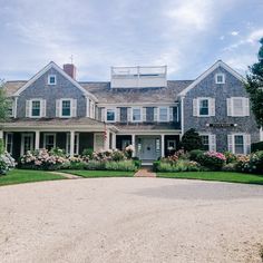 a large gray house with lots of flowers in the front yard