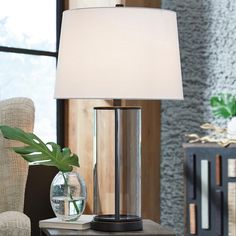 a lamp that is on top of a table next to a vase with a plant in it