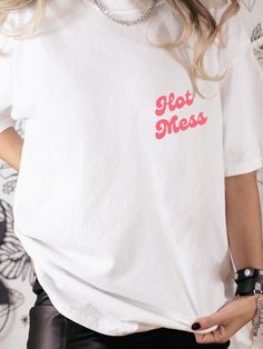 Hot mess- but make it cute. Choose from 6 colors with our Hot Mess graphic tee, printed on high quality Comfort Colors.  .: The Comfort Colors 1717 tee is made with medium fabric (6.1 oz/yd² (206.8 g/m consisting of high quality, 100% ring-spun US cotton for long-lasting comfort. .: The relaxed fit keeps the wearer comfy in both casual and semi-formal settings while the crew neckline delivers that classic, neat style which makes it perfect for accessorizing.  .: The pre-shrunk fabric ensures a consistently great fit. Check all available sizes in our Comfort Colors 1717 size chart.  .: All Comfort Colors 1717 shirts feature pre-shrunk cotton for size retention and a signature sewn-in twill label. .: Made using 100% US cotton that is ethically grown and harvested. Gildan is also a proud memb Funny Pink T-shirt With Text Print, Fun Crew Neck T-shirt With Funny Print, Red T-shirt With Funny Text For Summer, Funny White T-shirt With Letter Print, Cotton Crew Neck T-shirt With Letter Print, White Cotton Slogan T-shirt, Fun Red T-shirt With Letter Print, Fun Crew Neck Shirt With Screen Print, Cute Cotton T-shirt With Funny Print