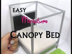 someone is holding up a miniature bed made out of an acrylic box with the words, easy miniaturan canopy bed