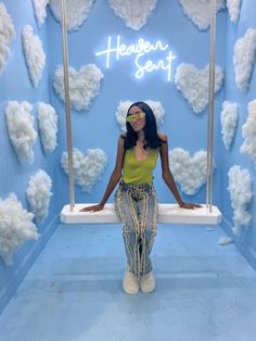 a woman standing in front of a blue wall with white clouds and hearts on it