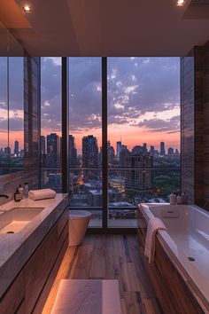 a bathroom with large windows and a view of the city at sunset or dawn,