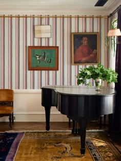 a grand piano in the corner of a room with striped wallpaper and paintings on the walls