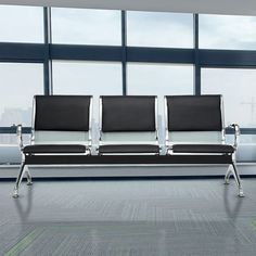 two black and white chairs sitting in front of large windows at an airport with no people