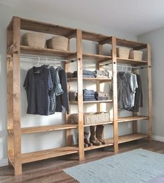 a wooden shelf filled with clothes next to a rug and wall mounted shoes rack in a room