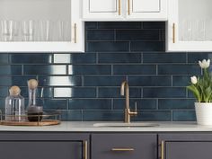 a kitchen with white cabinets and dark blue tile backsplash, gold handles, brass accents