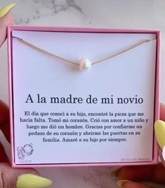 a person holding up a necklace with a message on it in a pink gift box