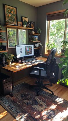 a home office with two computer screens and plants on the desk in front of large windows