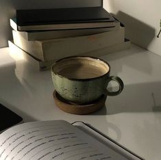 an open book sitting on top of a desk next to a coffee cup and books