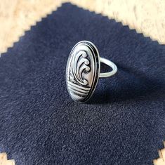 a silver ring sitting on top of a black cloth next to a piece of fabric