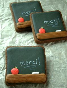 three cookies with writing on them are sitting on a sheet of wax paper and have been decorated to look like chalkboards