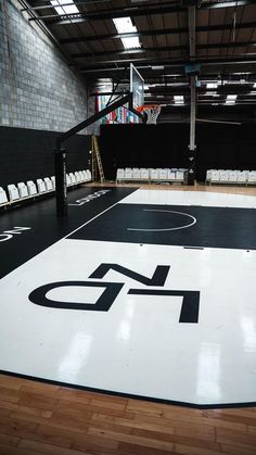 an indoor basketball court with white chairs and a black and white logo on the floor