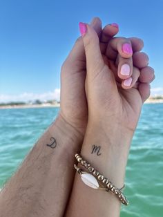 two people holding hands with tattoos on their wrists